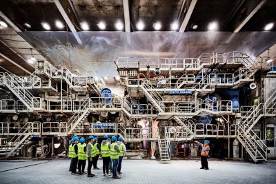 Visitors in hard hats beside a paper machine in a Holmen mill